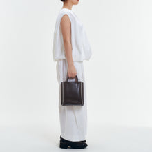 Load image into Gallery viewer, COURTNEY ORLA（コートニーオーラ）のCURVE TOTE S BLACK/CHOCOLATE BROWN（ハンドバッグ）のモデル着用写真
