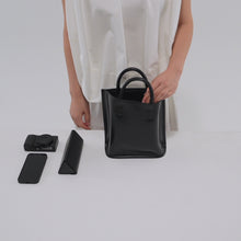 Load and play video in Gallery viewer, スマートフォン、コンパクトカメラ、ペンケースをCOURTNEY ORLA（コートニーオーラ）のCURVE TOTE S（ハンドバッグ）に入れる様子
